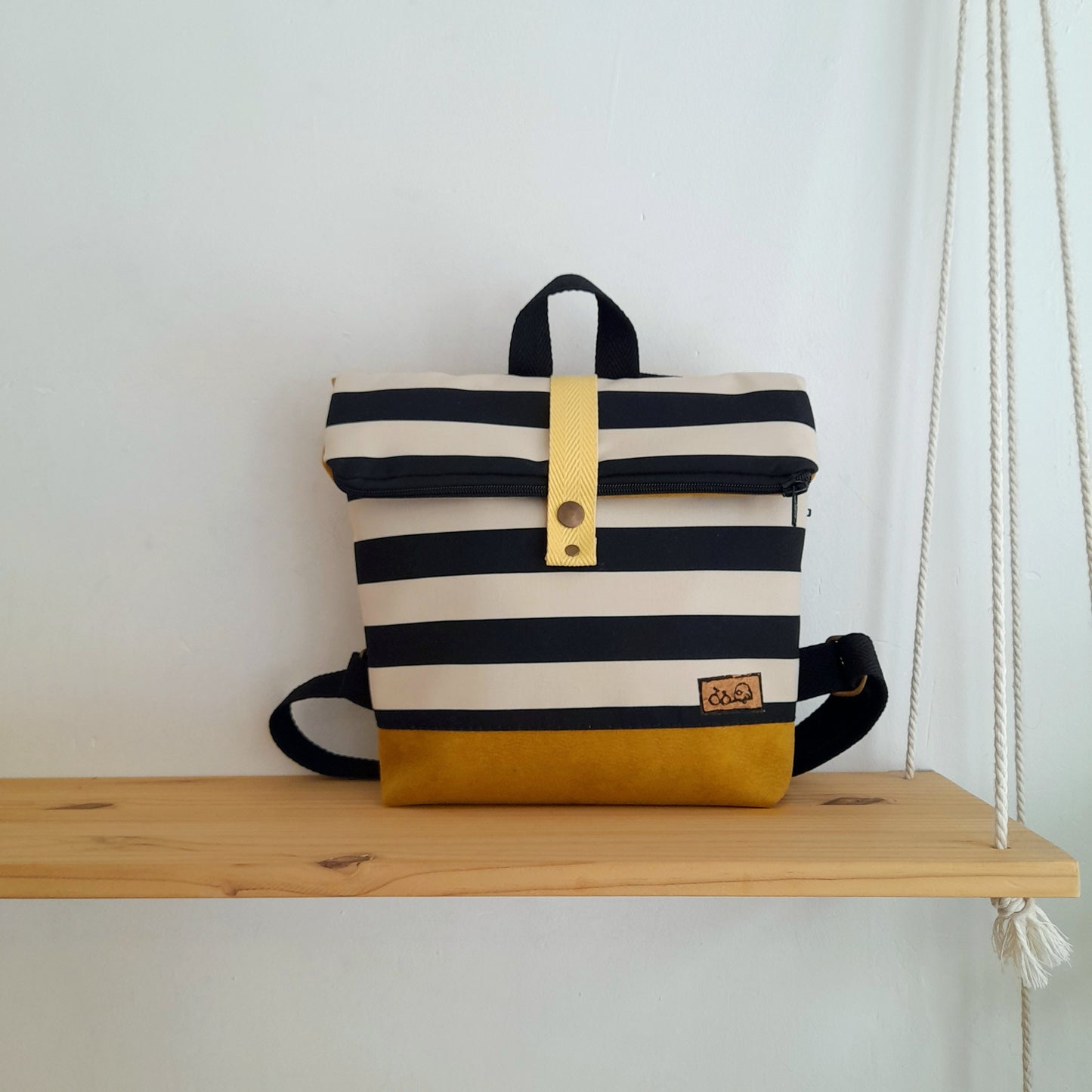 Mochila de solapa con rayas blanco y negro, y base mostaza