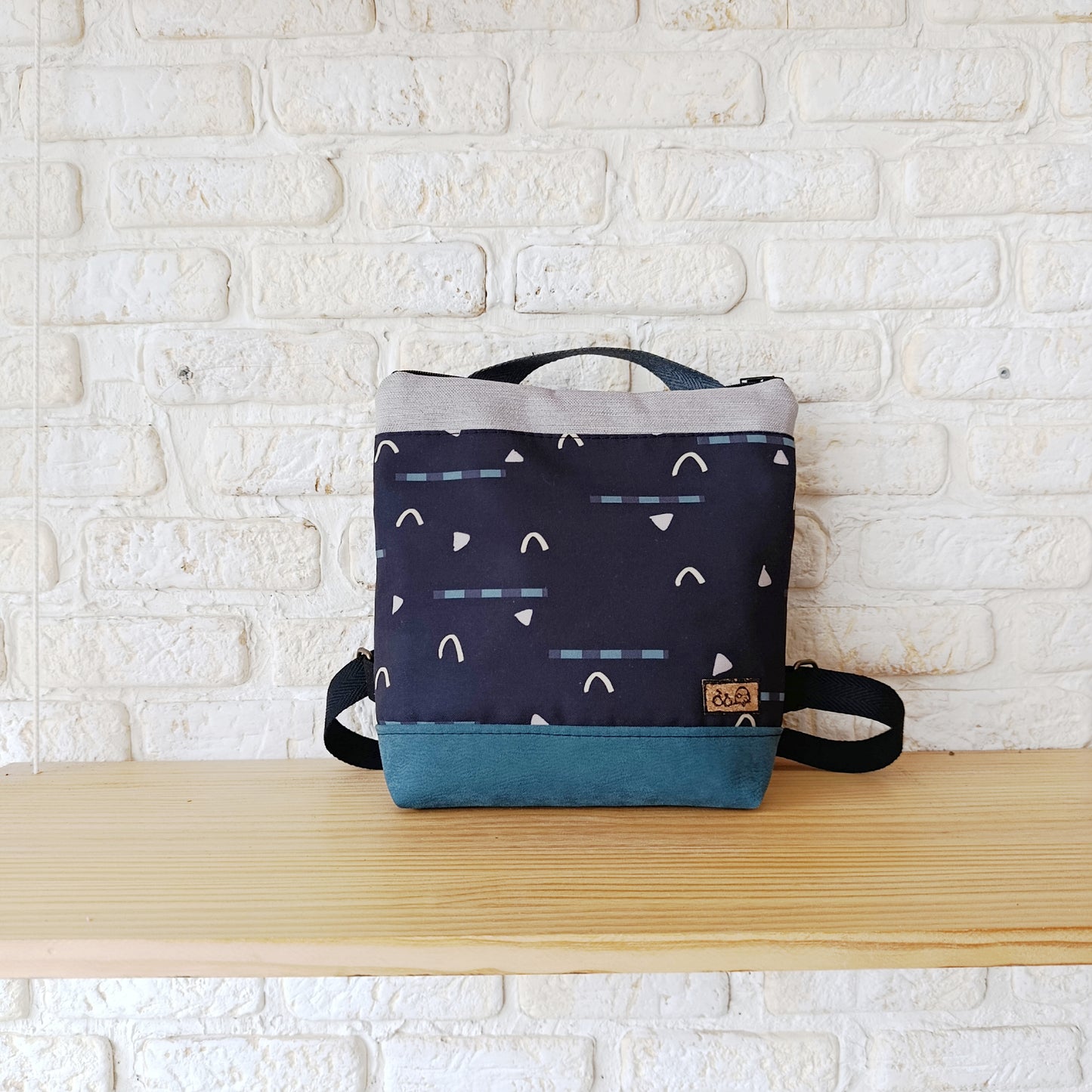 Mochila cuadrada de fondo negro, con azul y gris